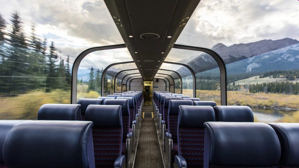A train car with blue seats and mountains in the background