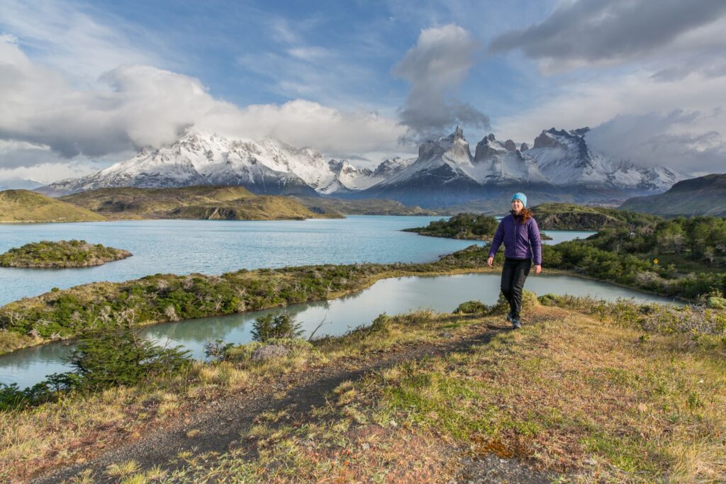 Person hiking along a path in front of mountains