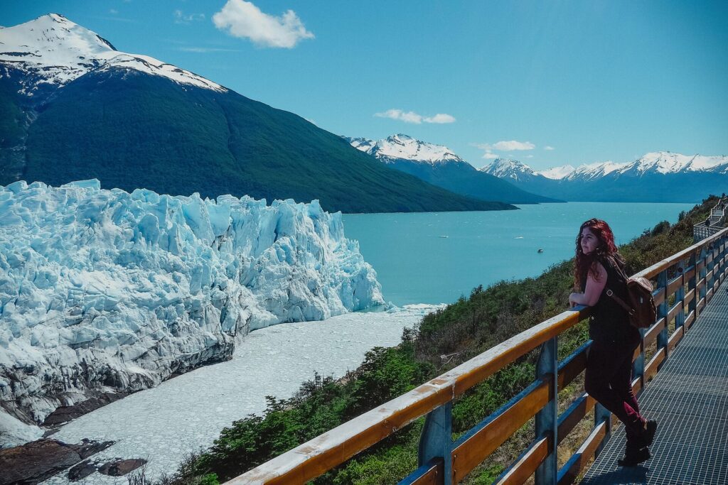 Woman standing by the railing overlooking a glacier