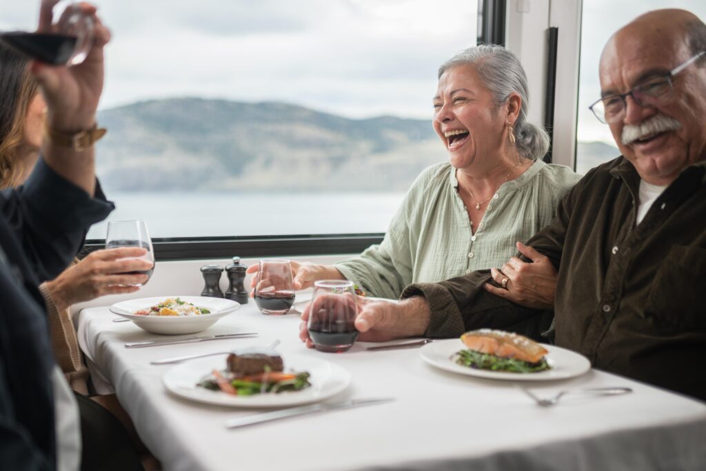 Guests socializing and eating lunch in GoldLeaf dining coach