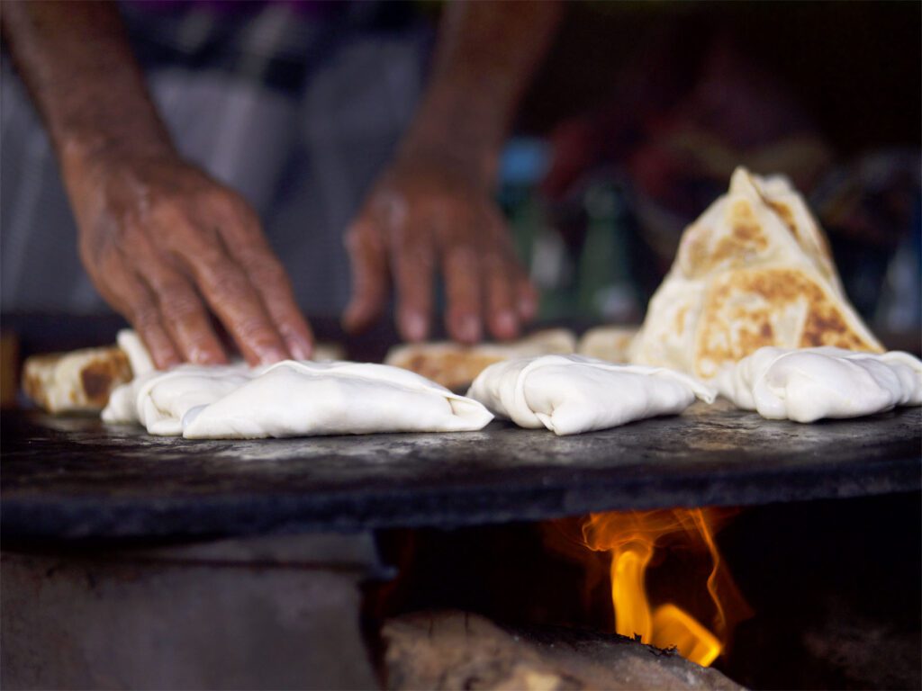 hands examining samosas cooking on hot plate