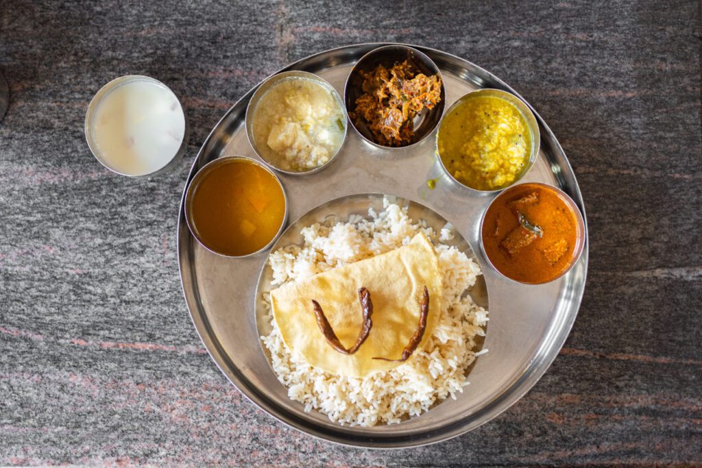 Meal made up of rice with a selection of different curries in tin containers