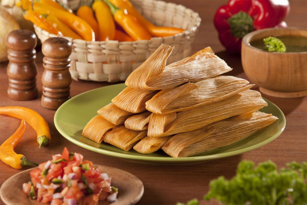 Traditional Tamales served with avocado and pico de gallo on mexican decoration