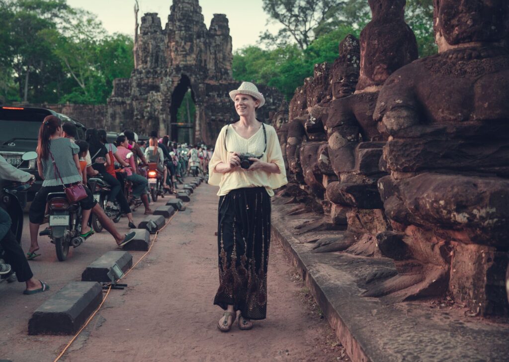 Female tourist walks among statues at sunset near Bayon Temple, near Angkor Wat