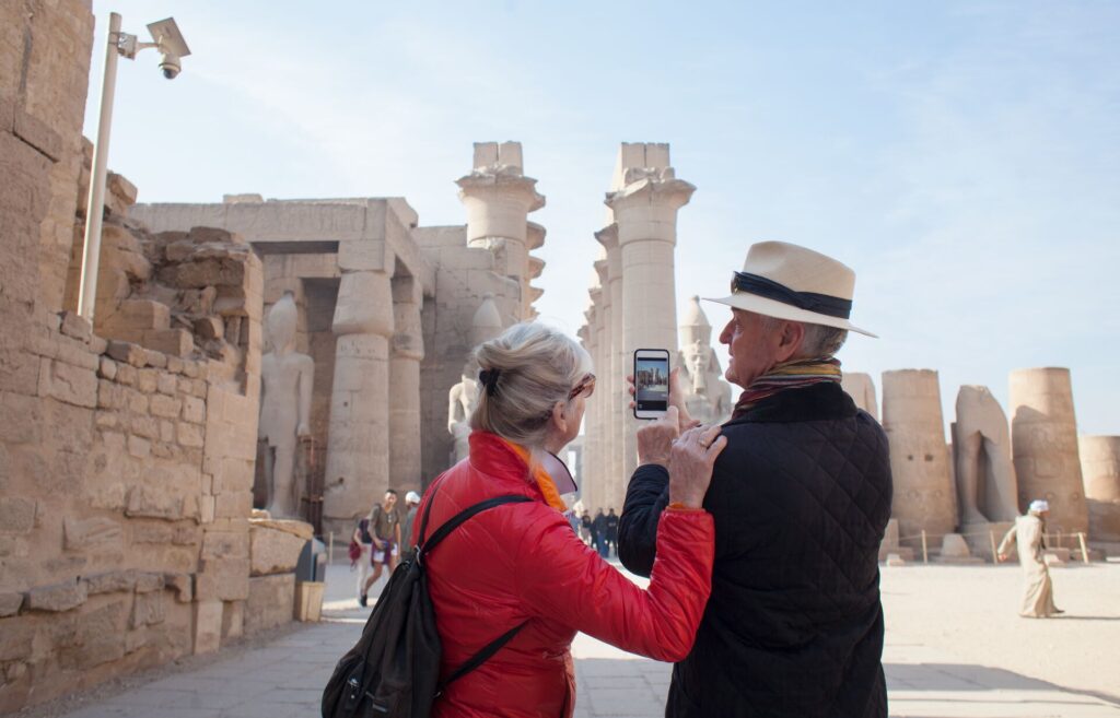 Happy elderly tourist couple taking pictures at the Temple of Luxor
