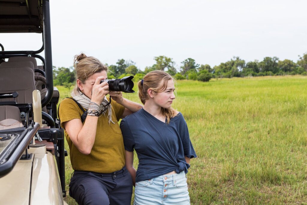 woman with teen by a safari vehicle with a camera