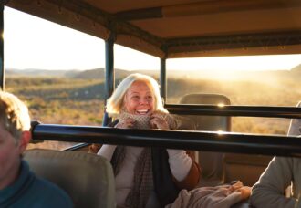 Happy senior woman on safari riding in off-road vehicle