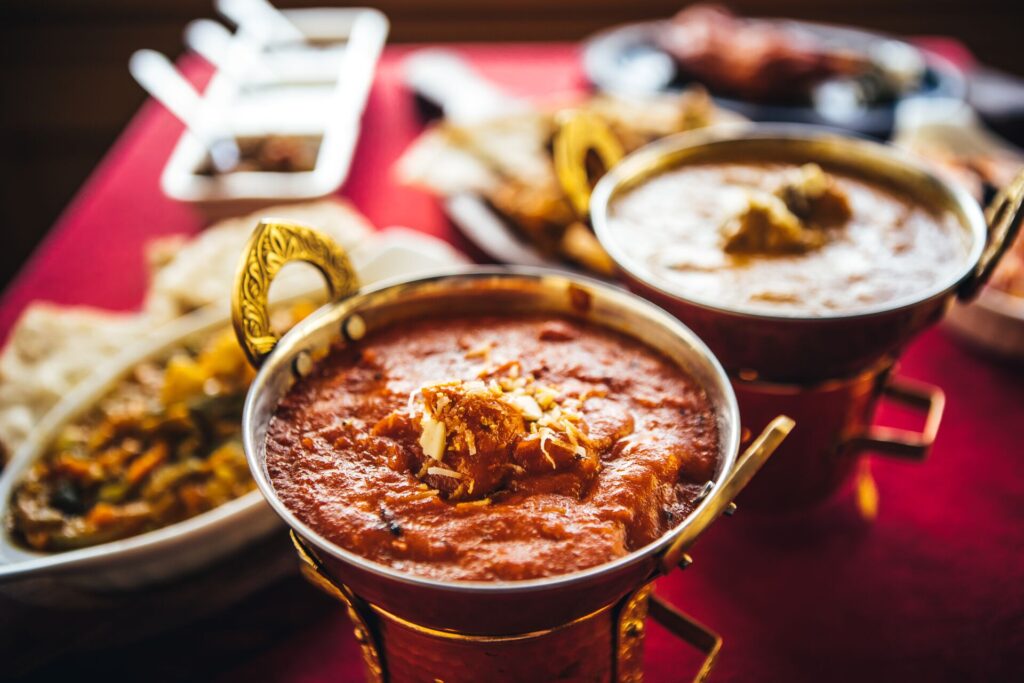Indian feast with butter chicken, chicken tandoori, lamb curry, vegetable curry, samosas, pakoras, bhajis, naan bread and basmati rice on a table Nort