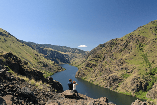 A couple standing on top of a mountain next to a river