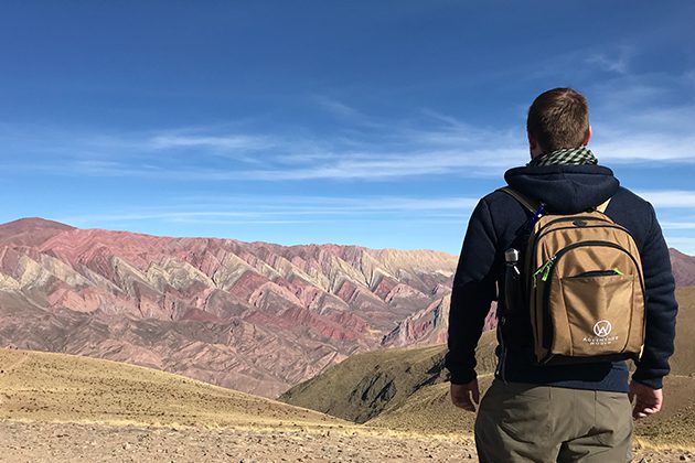A man with a backpack standing on a hill and watching mountains