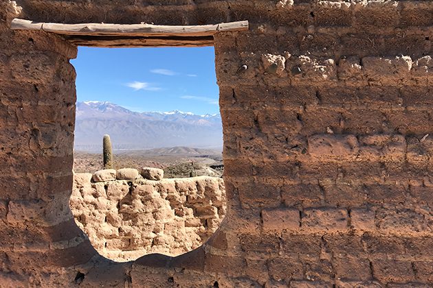 A window in a brick wall with a view of a mountain range