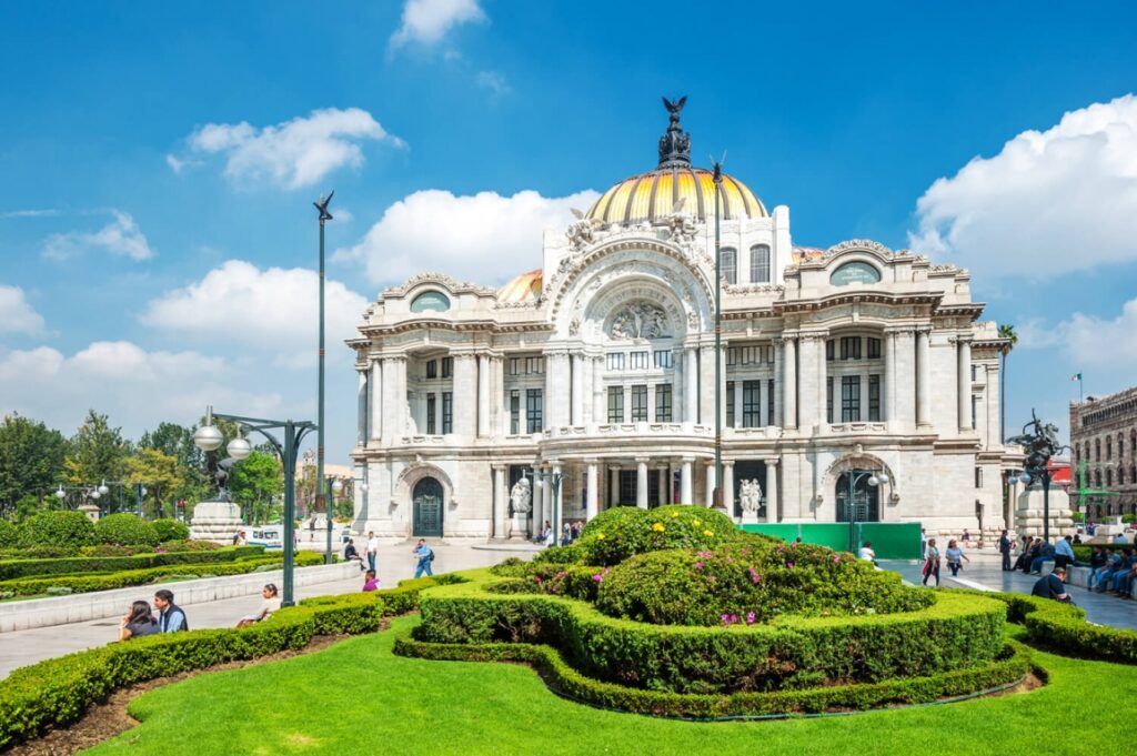 A large white building with a yellow dome on top of Palacio de Bellas Artes in Mexico