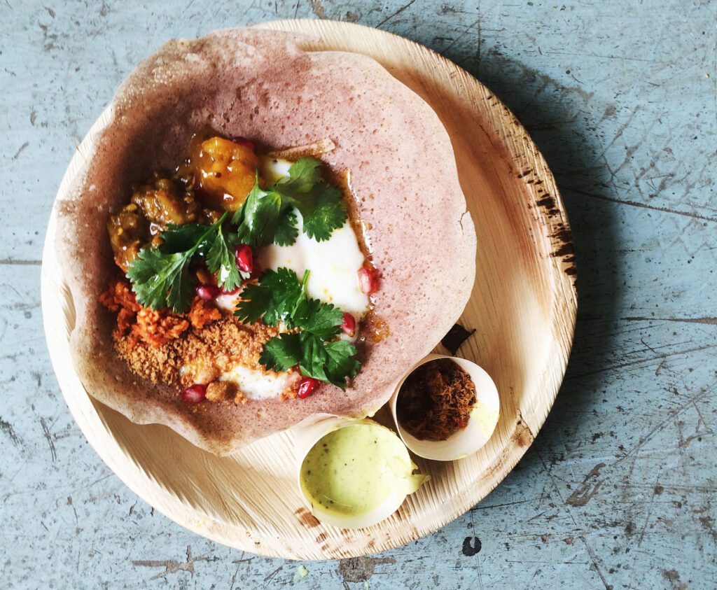 Sri Lankan egg hopper with toppings on a wooden plate