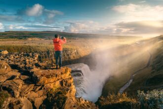 Person taking a photo of a waterfall below them