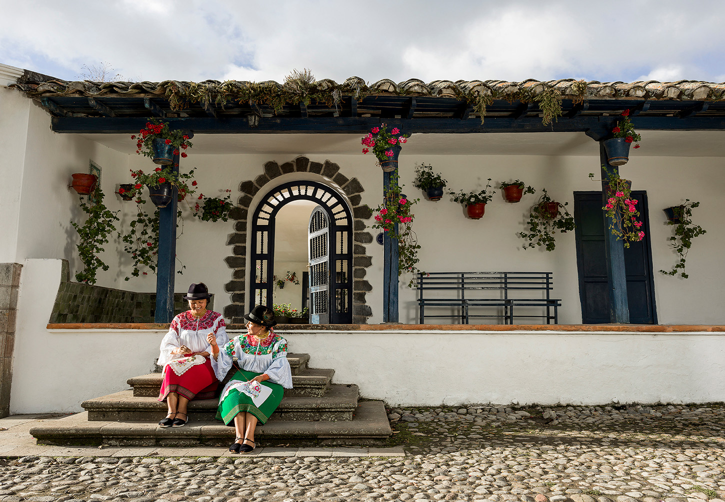 Two ladies sitting on the step of a colonial style building