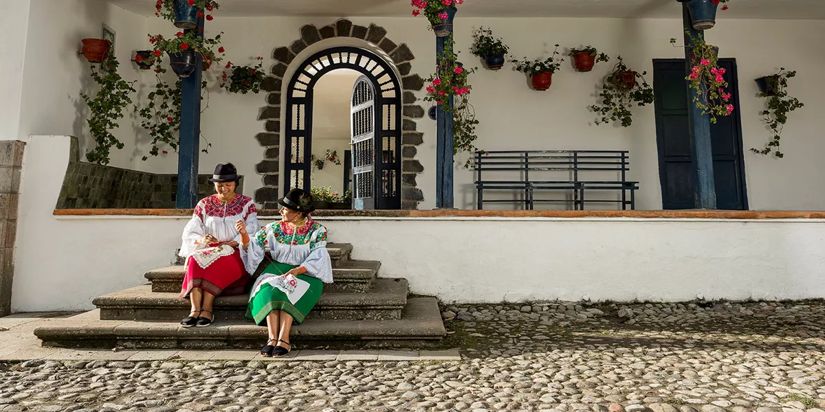 Two ladies sitting on the step of a colonial style building