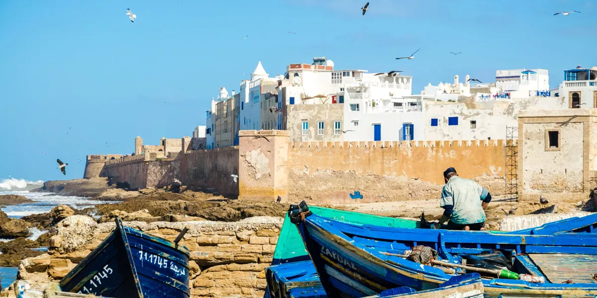 Site of a white city behind a wall with blue boats in the foreground