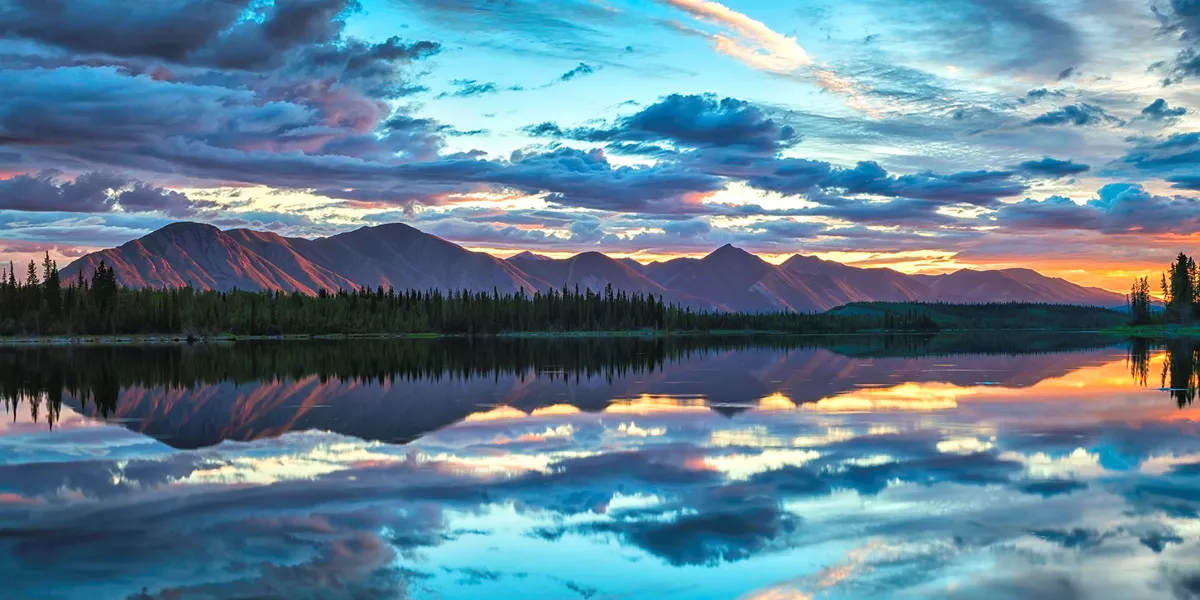 A lake with mountains in the background and clouds in the sky
