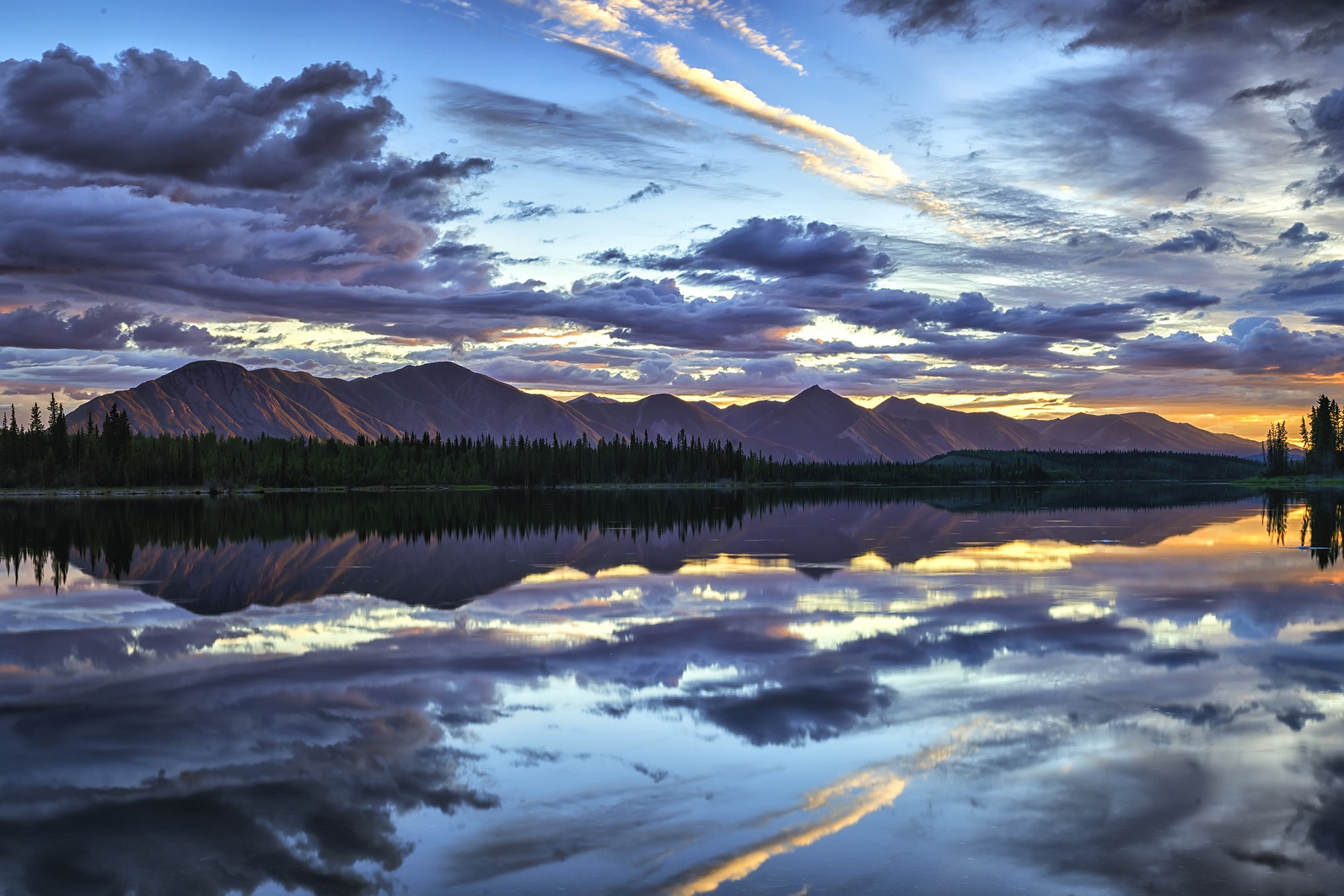 A lake with mountains in the background and clouds in the sky