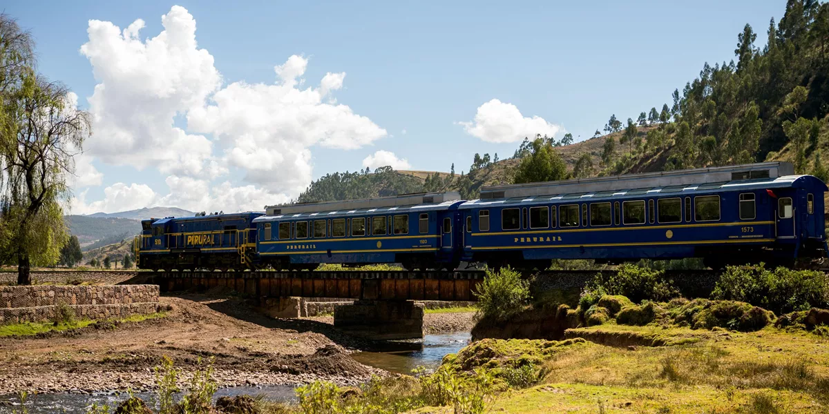 A blue and yellow train traveling over a bridge