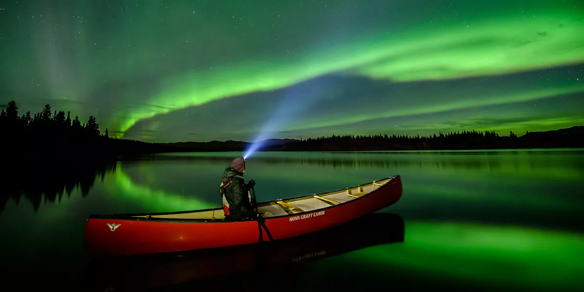 person in a canoe under the northern lights