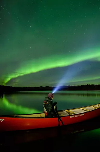 person in a canoe under the northern lights