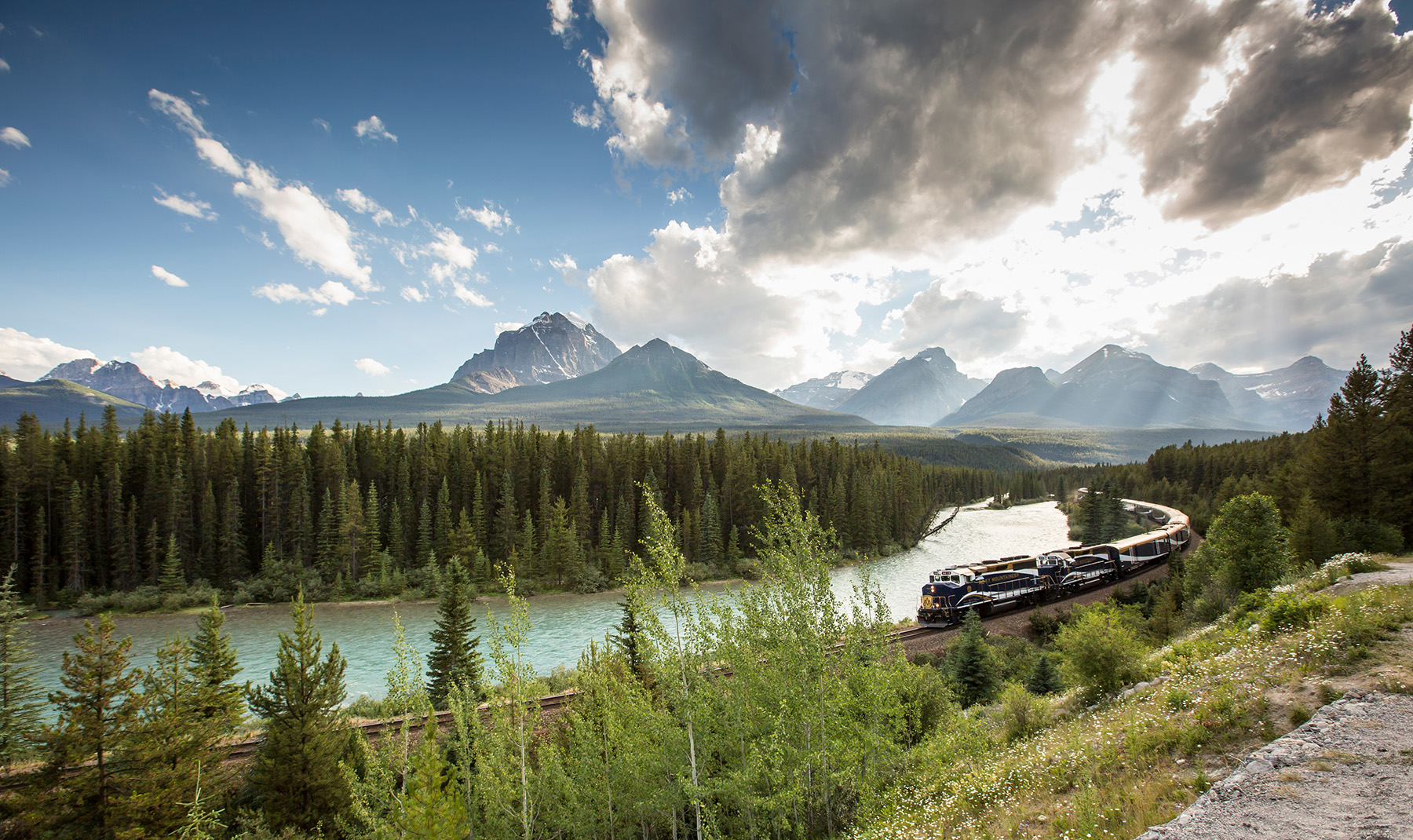 Train travelling along a curve with mountains in the background