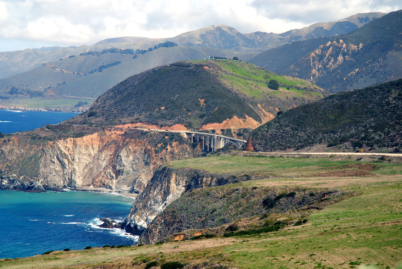 Road going through cliffs above water, across the USA West Coast