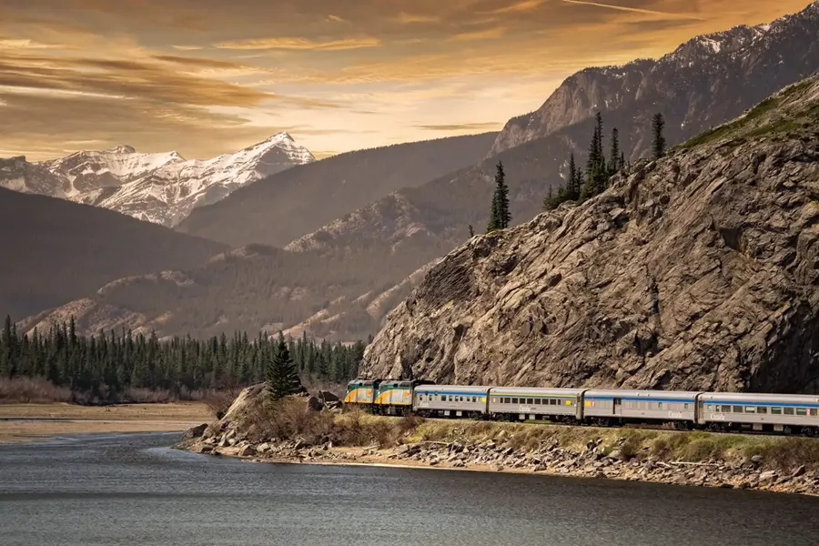 A train traveling along a mountain side next to a body of water