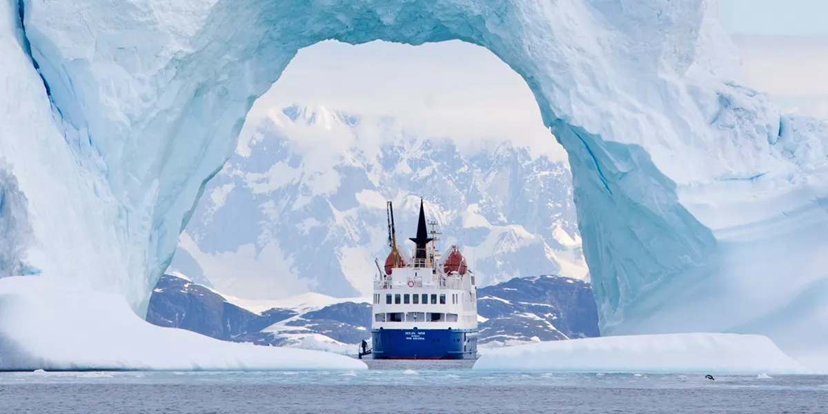 A boat in a body of water near an iceberg