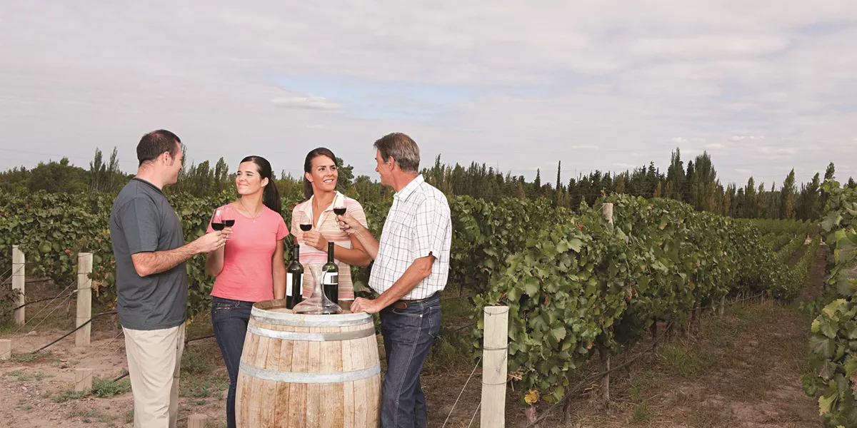 A group of people standing around a barrel of wine