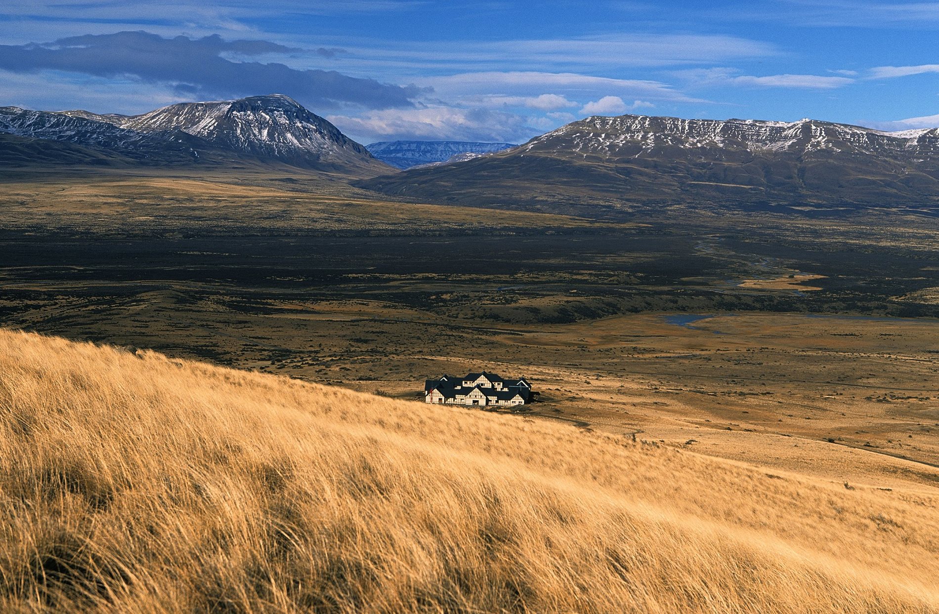 A house on a hill with mountains in the background