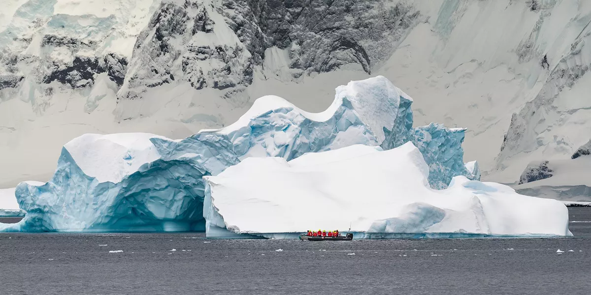 A boat in the water near a large iceberg