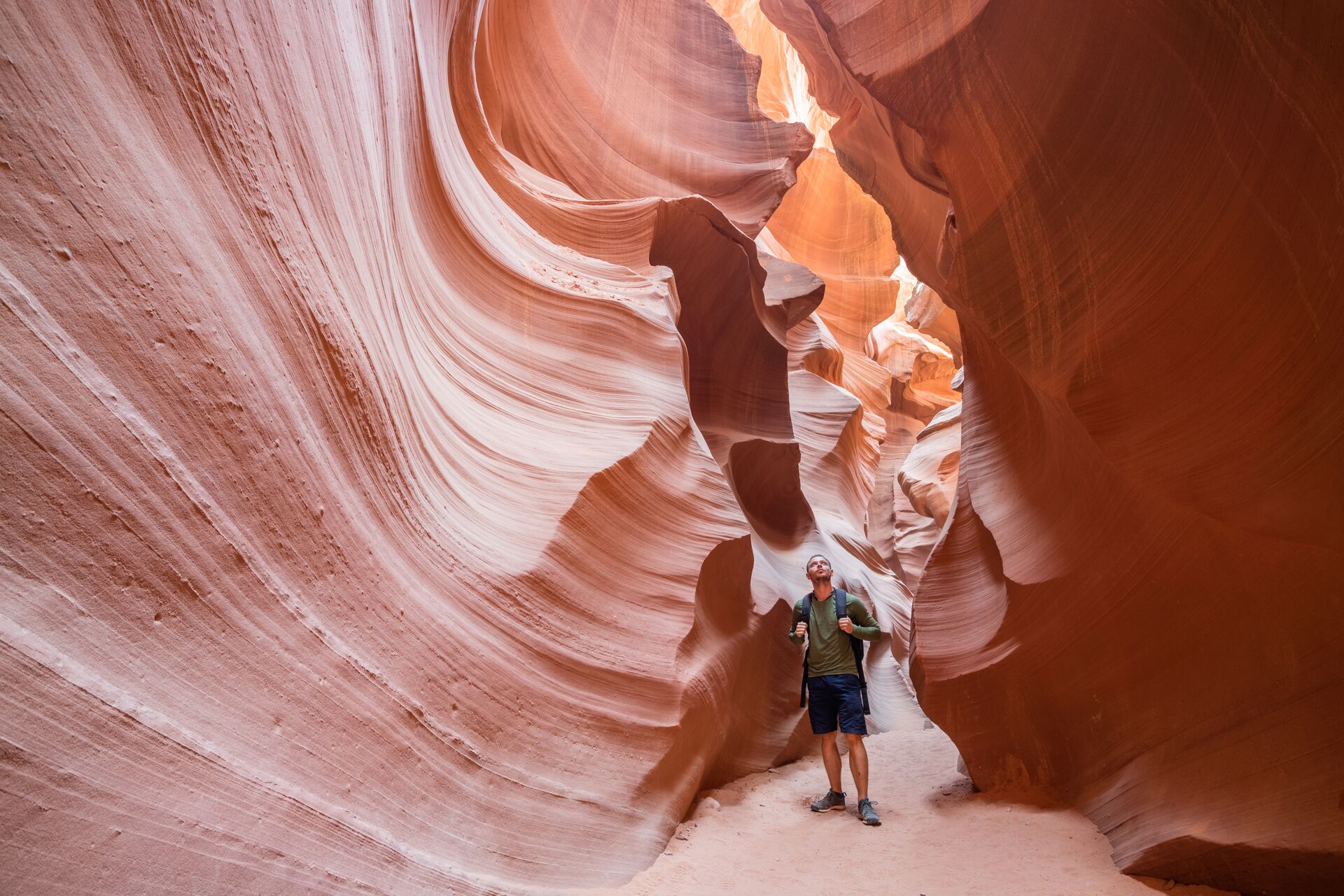 Hiker in narrow red rock canyon looking up