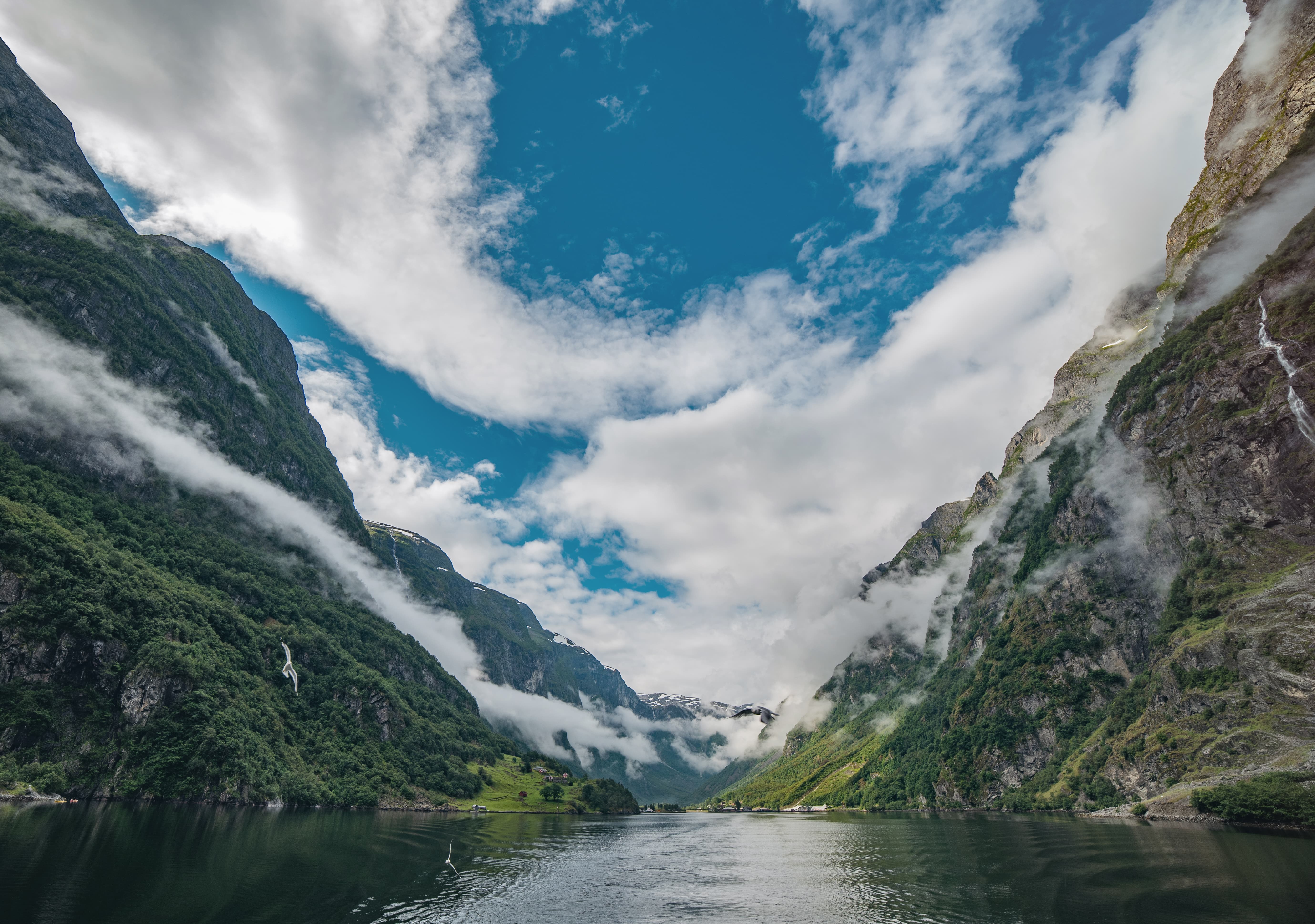 A body of water surrounded by mountains and clouds