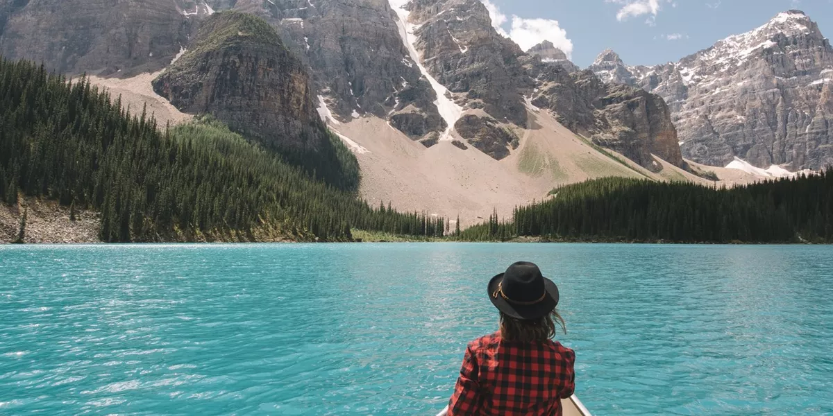 A person sitting on a boat in a lake looking at the Canadian Rockies