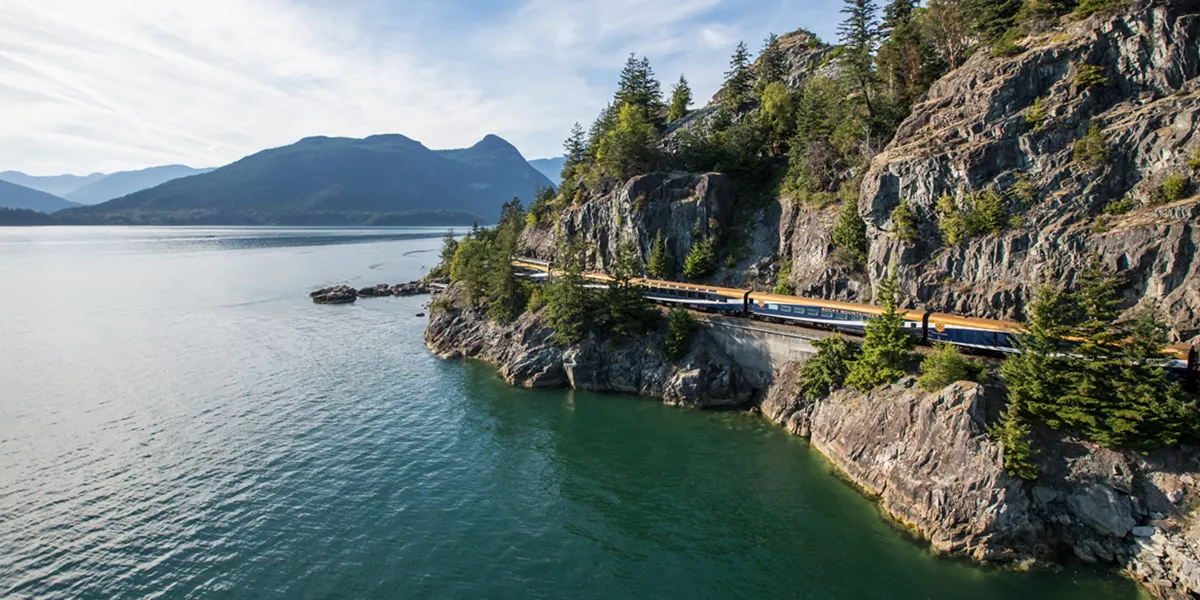 train along the coast at the base of a mountain