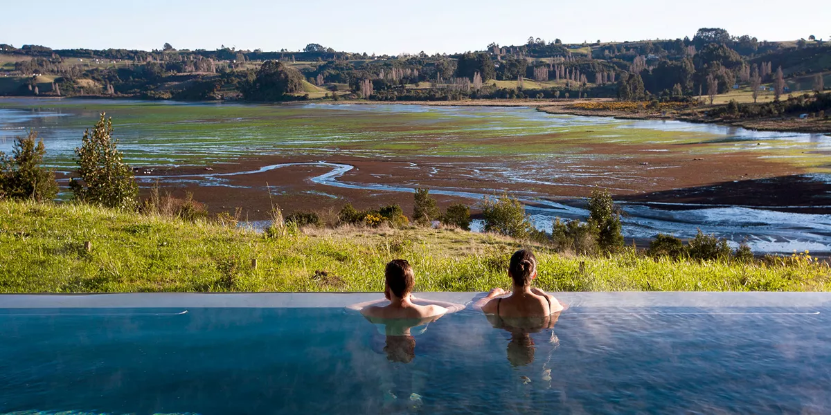 People in a pool overlooking a wild landscape
