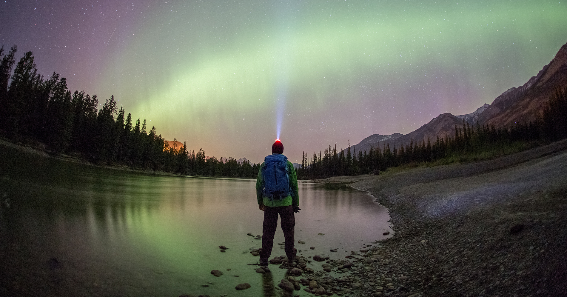 A person observing northern lights in the mountains